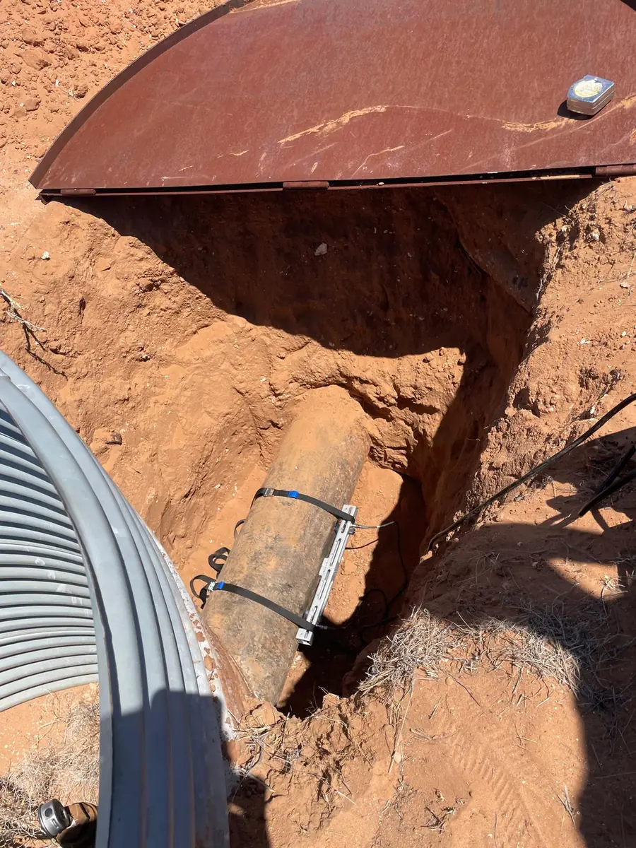 Portable clamp-on flow meter set up beside a large corrugated culvert pipe on a remote site
