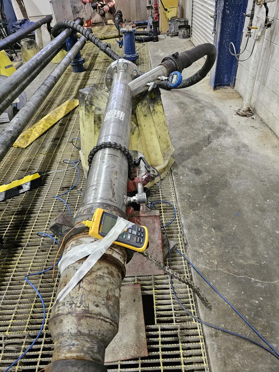 Close-up of a clamp-on ultrasonic transducer clamped to a process pipe with coupled cables