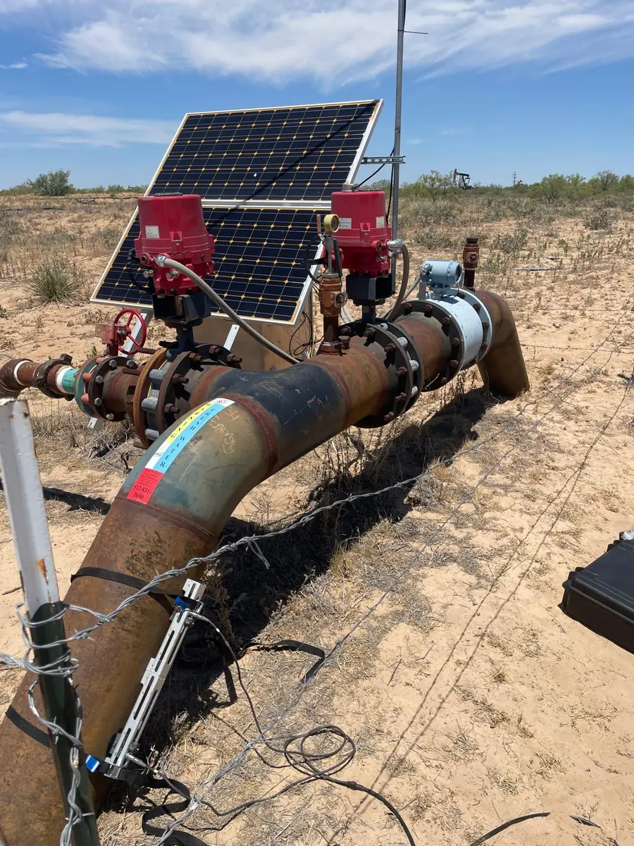Fixed clamp-on ultrasonic flow meter on a wellhead flowline powered by a solar panel in the West Texas desert